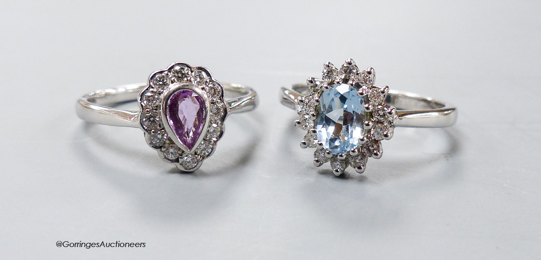 A modern 9ct white gold, pink sapphire and diamond cluster ring, size O and a similar blue topaz and diamond cluster ring, size N/O, gross 6.1 grams.